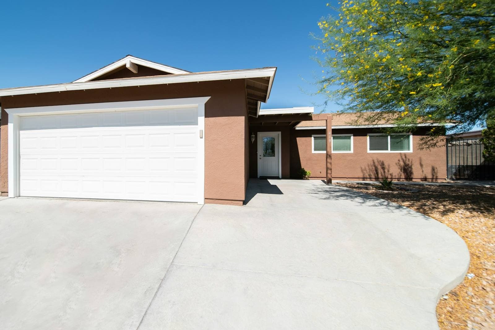A wide concrete driveway leading to a two-car garage on a single-story house