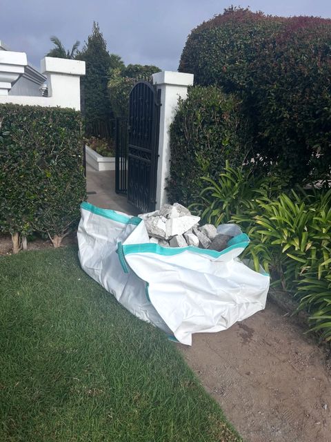 Dumpster bag of broken concrete beside a garden gate