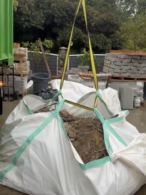 Crane slings hooked to a full bag of soil and roots