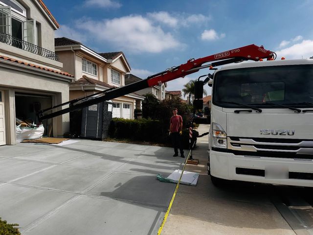Fassi crane reaching up a driveway to a bag at the garage