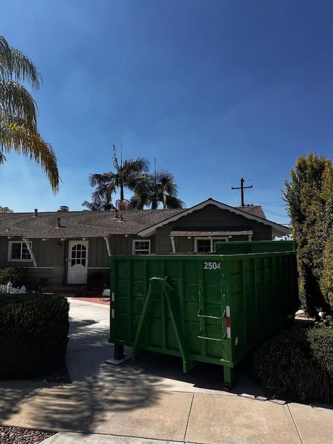 Green Eco Waste roll-off dumpster in a residential driveway